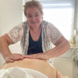 Tanja Moulton hält die Hände auf dem Rücken der Person auf einer Massageliege.