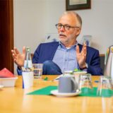 Matthias Müller erläutert in seinem Büro seine Entscheidung: Vor ihm auf dem Tisch eine Kaffeekanne und Wasser, er selbst trägt Jeans, ein blaues Jackett und ein blau-weiß gestreiftes Hemd.