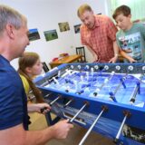 Zwei Männer und zwei Kinder spielen an einem Tischkicker.
