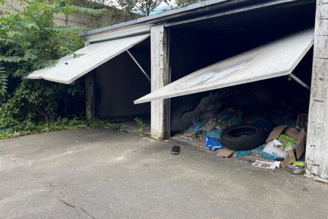 Die Garagentore hängen immer noch halb geöffnet herab, in den Garagen lagert Müll.
