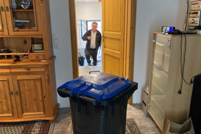 Der Brasserter Andreas Kuttke hat die Wohnungstür zur Straße geöffnet und zieht die Mülltonne aus dem Wohnzimmer durch den Flur zum Leerungsplatz auf dem Bürgersteig.