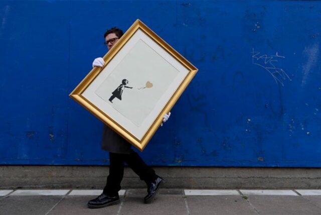 Ein Mann trägt das Bild «Girl with Balloon» des britischen Streetart-Künstlers Banksy. Der Siebdruck in Schwarz und Gold wird vom 11. bis 24. September 2019 von dem Auktionshaus Christie’s online unter Devise: „Banksy: I can’t believe you morons actually buy this sh*t“ zusammen mit anderen Kunstwerken von Banksy versteigert.