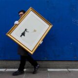 Ein Mann trägt das Bild «Girl with Balloon» des britischen Streetart-Künstlers Banksy. Der Siebdruck in Schwarz und Gold wird vom 11. bis 24. September 2019 von dem Auktionshaus Christie’s online unter Devise: „Banksy: I can’t believe you morons actually buy this sh*t“ zusammen mit anderen Kunstwerken von Banksy versteigert.