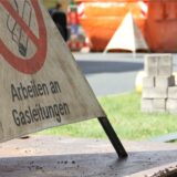 Eine Baustelle mit einem Schild im Vordergrund, auf dem „Arbeiten an Gasleitungen“ steht.