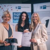 Zwei Frauen der IHK verleihen eine Urkunde an eine Auszubildende.