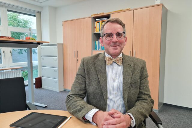 Schulleiter Christian Krahl des Joseph-König-Gymnasiums in Haltern sitzt an einem Tisch im Schulbüro.