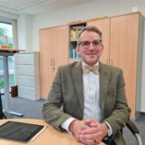Schulleiter Christian Krahl des Joseph-König-Gymnasiums in Haltern sitzt an einem Tisch im Schulbüro.