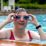 Eine Frau ist im Freibad des Hertener Copa Backum am Beckenrand und richtet ihrer Schwimmbrille, um die nächste Bahn ziehen zu können.