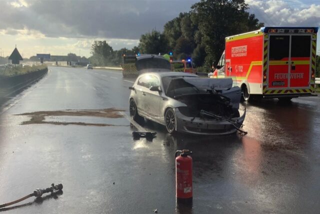 Unfallfahrzeug und Rettungswagen auf der A42 im Gegenlicht.