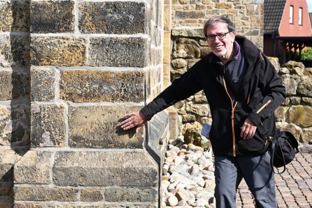 Christian Gruber zeigt an einer Mauer auf die Jahreszahl 1854.