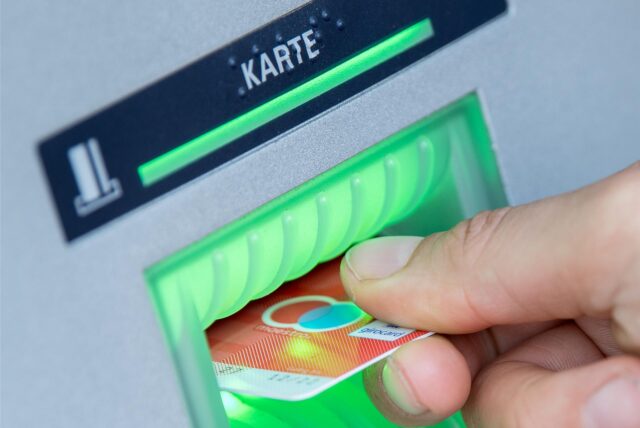 Eine EC-Karte wird in den Schlitz eines Geldautomaten gesteckt.