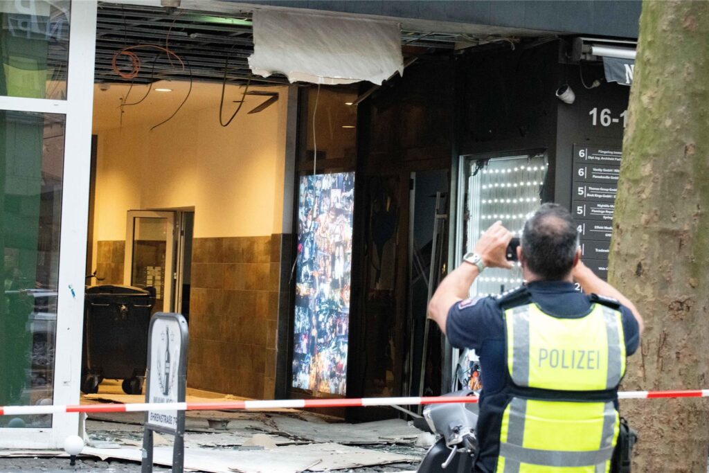 Polizeibeamte stehen nach einer Explosion vor einem beschädigten Gebäude in der Innenstadt am Hohenzollernring. Über mögliche Verletzte oder die Ursache der Explosion machte die Polizei zunächst keine Angaben. Polizeibeamte stehen nach einer Explosion vor einem beschädigten Gebäude in der Innenstadt am Hohenzollernring. Über mögliche Verletzte oder die Ursache der Explosion machte die Polizei zunächst keine Angaben.