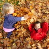Zwei Kinder spielen im Laub.