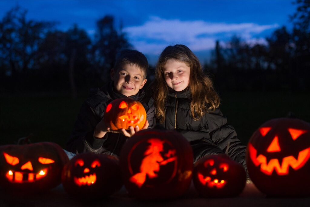 Kinder schauen sich leuchtende Halloween-Kürbisse an. Kinder schauen sich leuchtende Halloween-Kürbisse an.