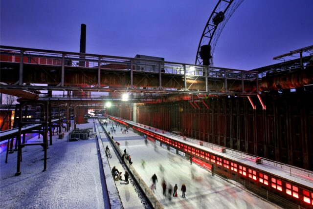Zahlreiche Besucher fahren auf der Eisbahn Kokerei Zollverein in Essen mit ihren Schlittschuhen