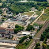 Ein Luftbild von einem ehemaligen Zechenstandort. Der hintere Teil der Fläche liegt brach und ist begrünt. Dahinter ist die Emscher zu sehen.