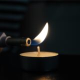 Ein Teelicht wird mit einem Feuerzeug entzündet.