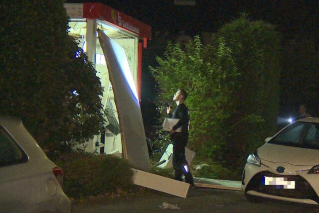 Ein Ermittler leuchtet mit einer Taschenlampe in einen gesprengten Geldautomaten