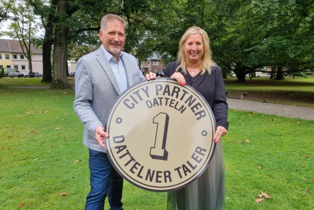 Zwei Personen halten den Dattelner Taler hoch.