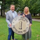 Zwei Personen halten den Dattelner Taler hoch.