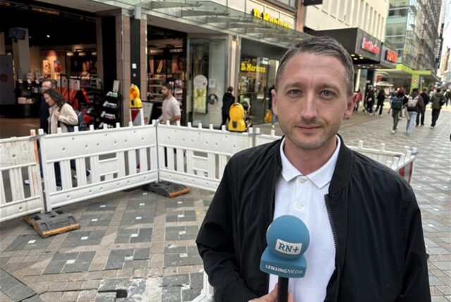 Reporter Philipp Pohl steht mit einem Mikrofon vor der abgesackten Stelle auf tmunder  Westernhellweg