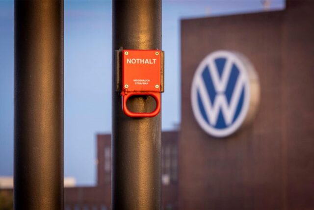 Ein Schalter mit der Aufschrift «Nothalt» ist am Morgen am Bahnhof vor einem Logo am Volkswagen Stammwerk zu sehen.