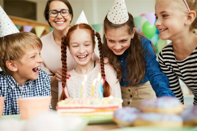 Auf einem Kindergeburtstag freuen sich die Gäste über den Geburtstagskuchen.
