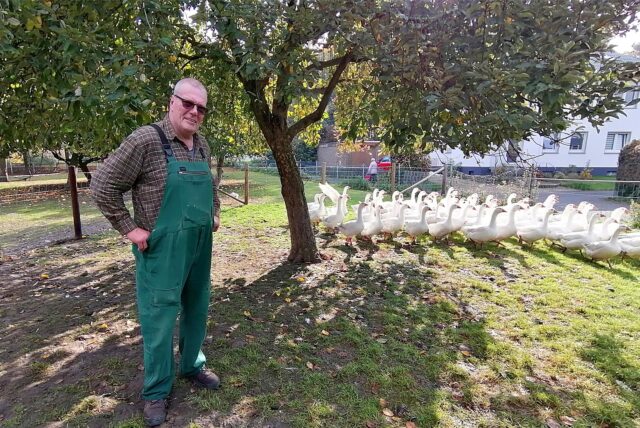Ulrich Dingebauer mit Gänsen auf einer Wiese des Deininghauser Hofes.