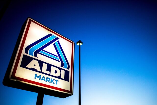 Eine Reklame mit dem Logo von Aldi Nord leuchtet neben einer Straßenlaterne.
