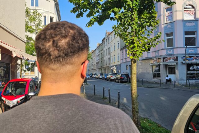 Ein Mann steht mit dem Rücken zur Kamera an einer Straße in der Dortmunder Nordstadt.