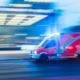 Ein Krankenwagen mit Blaulicht fährt an einer Straße vorbei.