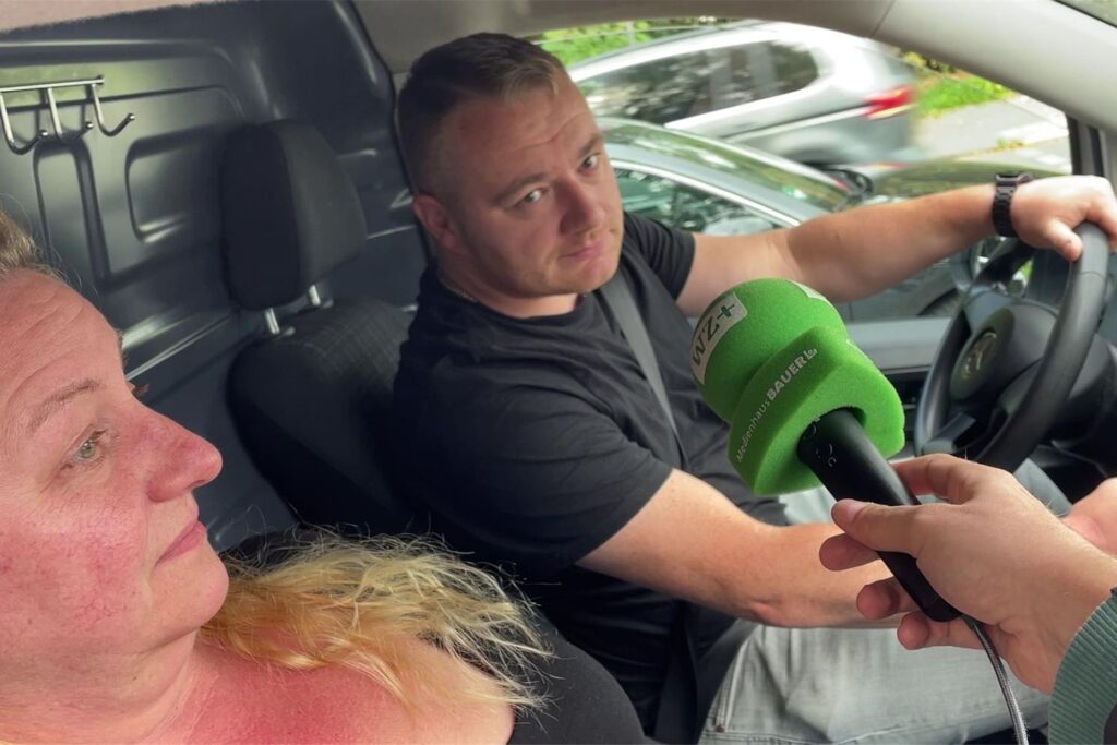 Ein Paar sitzt im Auto, ein Reporter hält ein Mikrofon hinein und führt ein Interview. Ein Paar sitzt im Auto, ein Reporter hält ein Mikrofon hinein und führt ein Interview.
