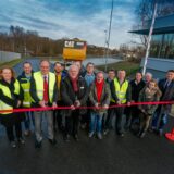 Vertreter von Caterpillar und Stadt stehen bei der Einweihung der Caterpillarstraße hinter einem symbolischen Absperrband.