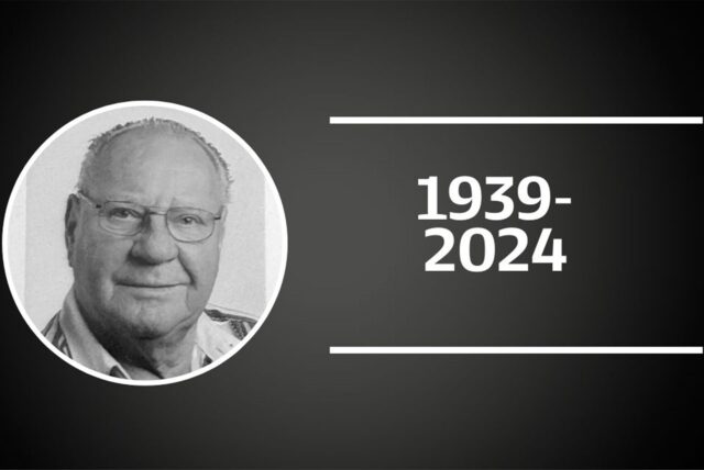 Ein Schwarzer Hintergrund auf dem ein weiß umrandeter Kreis auf der linken Seite ein schwarz weißes Bild von Karl-Heinz Drygala zeigt. Auf der rechten Seite sind in weißen Ziffern die Jahreszahlen 1939 und 2024 von horizontalen weißen Linien oben und unten eingerahmt.