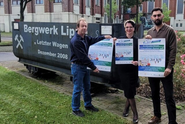 Ulrich Beer von der „Galerie im Rahmen“ (l.), Jessica Zubala vom Stadtteilbüro und Ugur Keklik von „Crescent“ halten Plakate für den Trödelmarkt auf dem Kauenhof der Zeche Westerholt in die Kamera.