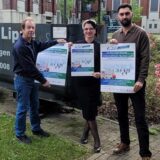 Ulrich Beer von der „Galerie im Rahmen“ (l.), Jessica Zubala vom Stadtteilbüro und Ugur Keklik von „Crescent“ halten Plakate für den Trödelmarkt auf dem Kauenhof der Zeche Westerholt in die Kamera.