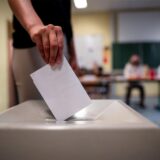 Eine Frau wirft einen Wahlschein in eine Wahlurne.