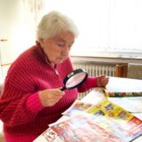 Die Hertenerin Gisela Riepenhoff blickt beim Lesen von Prospekten durch eine Lupe.