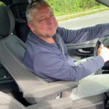 Ein Mann sitzt hinter einem Lenkrad im Auto.
