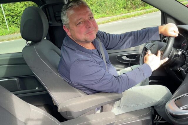 Ein Mann sitzt hinter einem Lenkrad im Auto.