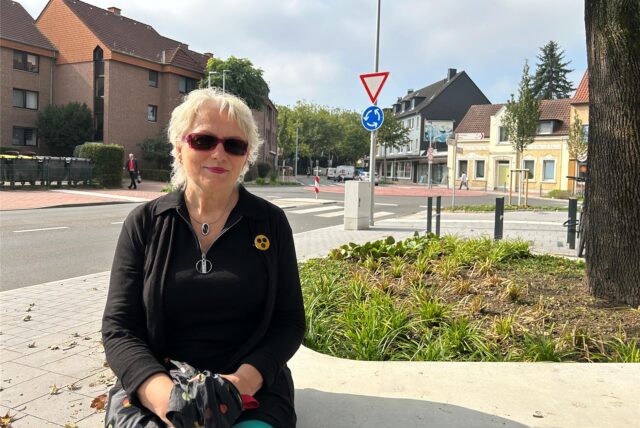 Cornelia Tollkamp-Schierjott sitzt auf einer Bank vor dem Kreisverkehr.