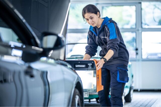 Frau macht eine technische Überprüfung der Leuchtkomponente am Auto