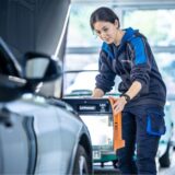 Frau macht eine technische Überprüfung der Leuchtkomponente am Auto