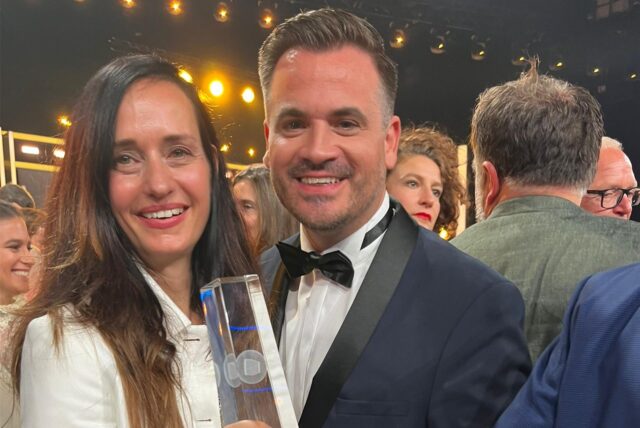 Christoph Pellander und Kollegin Carolin Haasis halten einen Pokal aus Glas in der Hand.