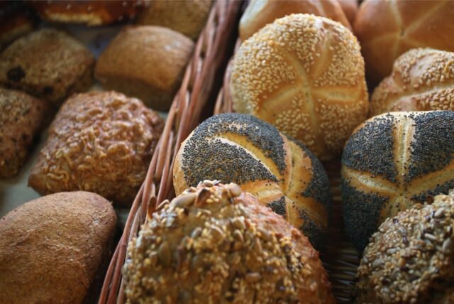 Verschiedene Brötchen liegen in der Auslage eines Bäckers.