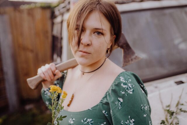 Die Singer-Songwriterin Slaughterin Daisies hält eine Axt in der Hand, sie steht beim Auftakt der Sparkassen-Clubraum-Contests im Treffpunkt Altstadt auf der Bühne.
