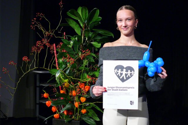 Wioletta Litvinov steht mit einer Urkunde und einem blauen Luftballon in den Händen auf der Bühne der Stadthalle Datteln.