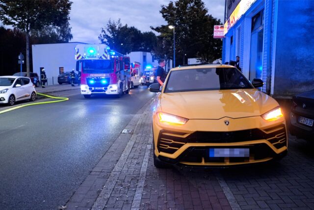 Ein gelber Sportwagen steht auf einem Geh- und Radweg, dahinter Feuerwehrleute im Brandeinsatz in Herten.
