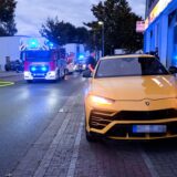 Ein gelber Sportwagen steht auf einem Geh- und Radweg, dahinter Feuerwehrleute im Brandeinsatz in Herten.