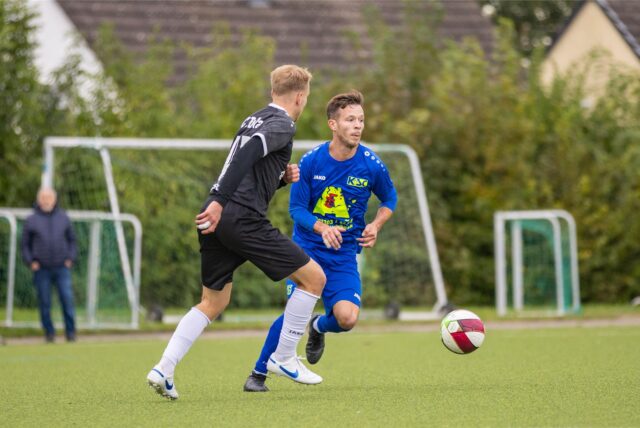 Zwei Fußballer rennen einem Ball hinterher.